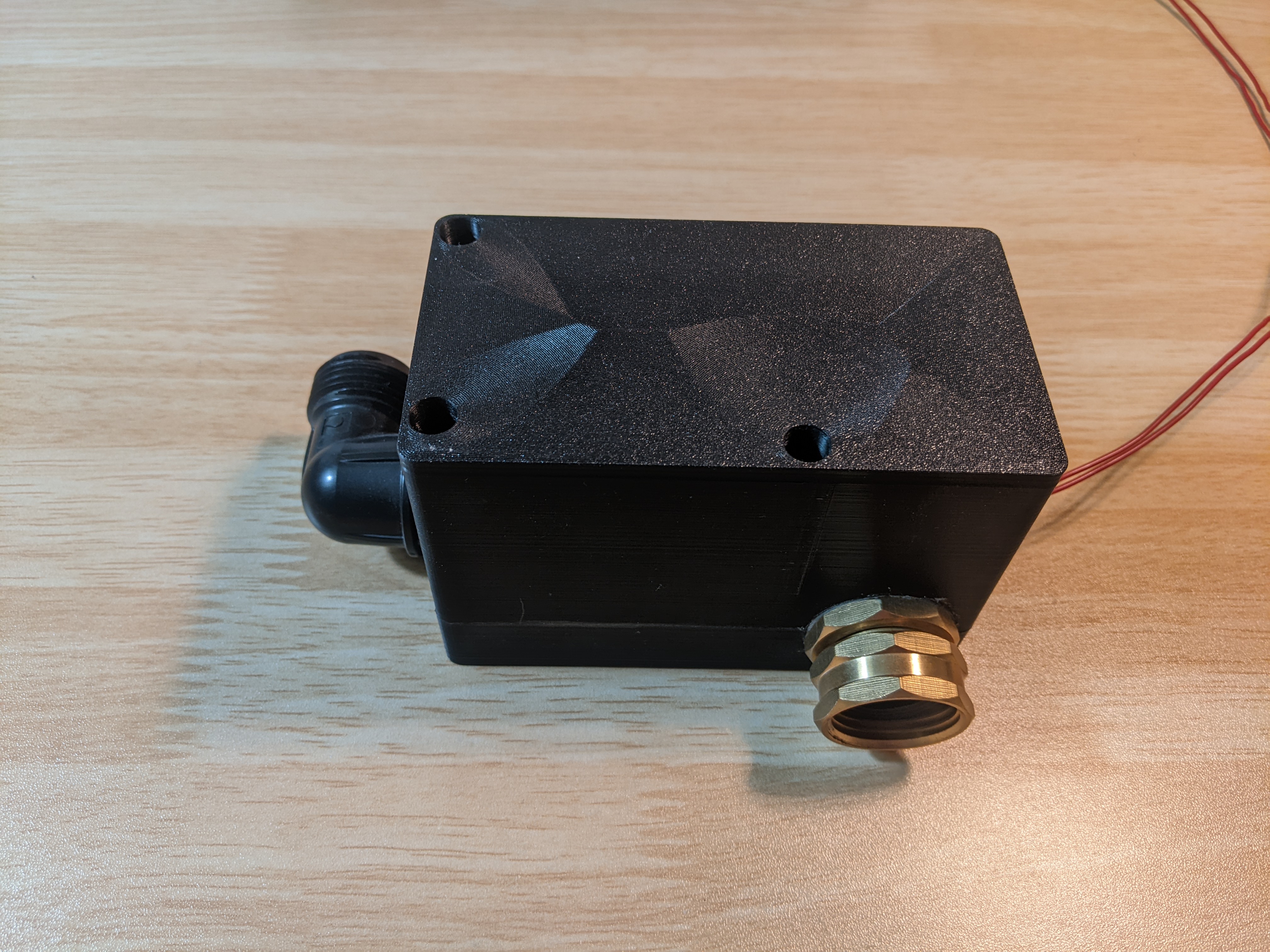 An external view of the solenoid. It is a black box with two hose fittings, one on each end.